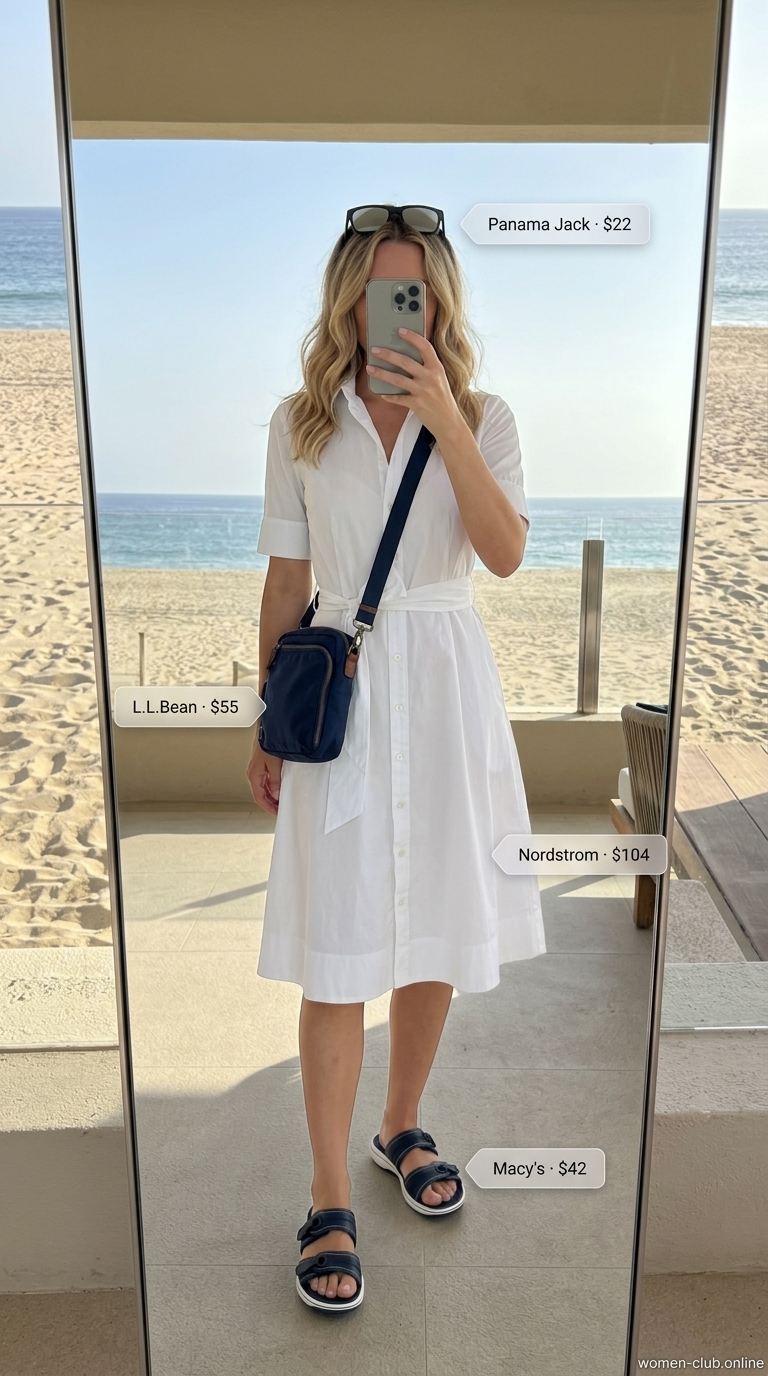 Chic summer beach outfit for women 2026: White oversized shirt dress, navy crossbody, black sunglasses.