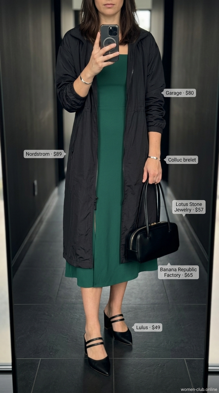 Emerald green midi dress with a black windbreaker for women 2026, sophisticated rainy day style.