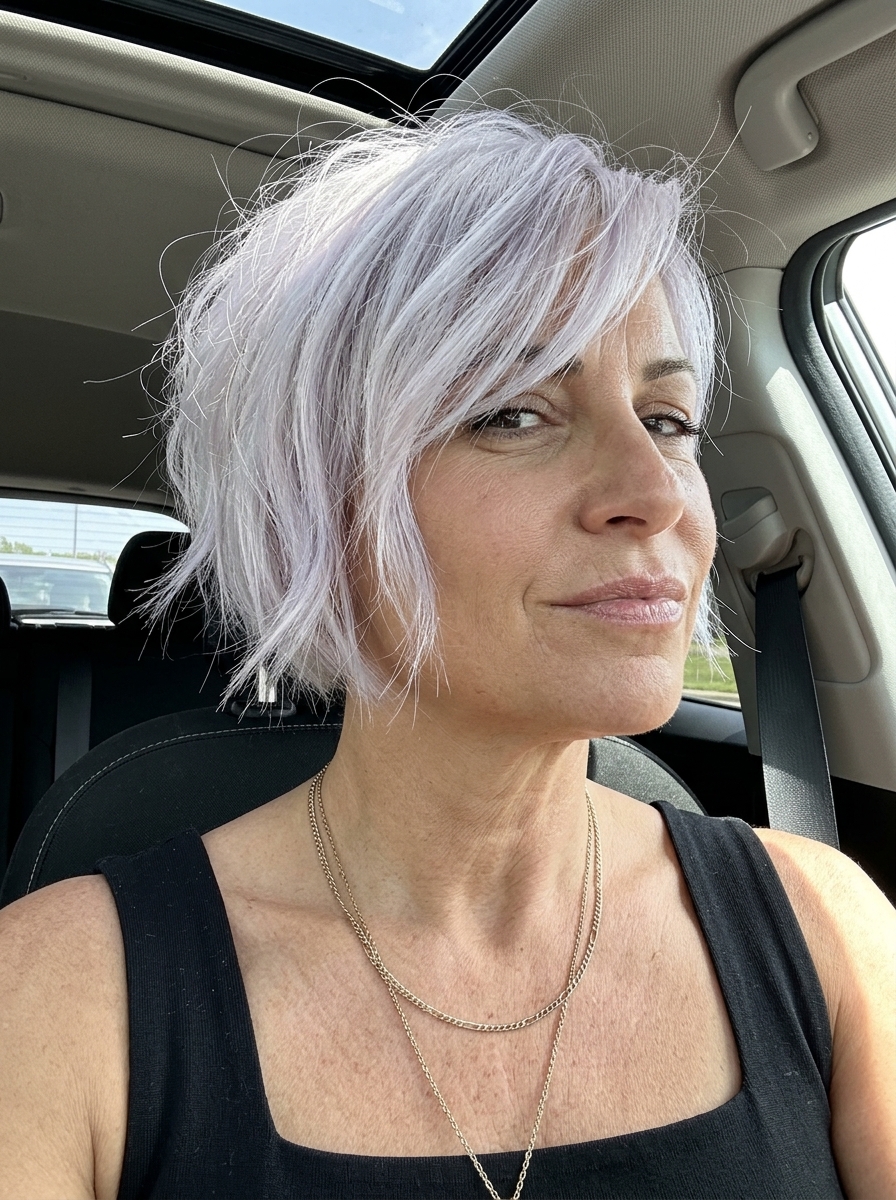 very short textured crop haircut with icy platinum blonde, cool white, violet undertones, side-swept fringe — edgy, bold