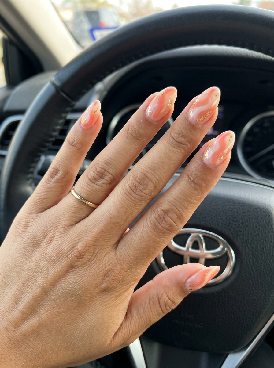 Soft coral swirls medium almond nails for summer vacation, with creamy white and gold foil. Bohemian and artistic simple summer acrylic nail designs 2026.
