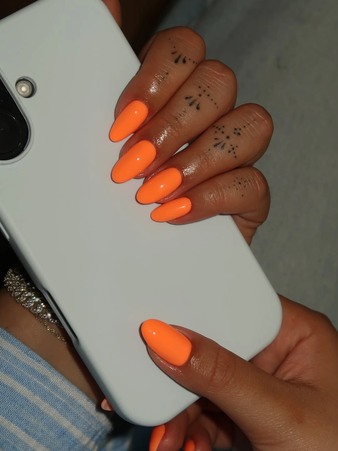 bright orange almond nails with tiny dark accents