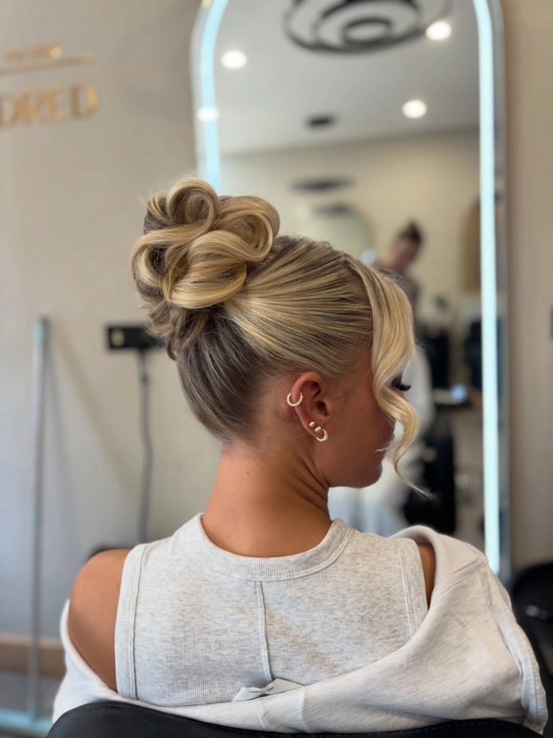 Fall hairstyles for wedding guests 2026 Modern High Loop Bun with Soft Blonde Elegance