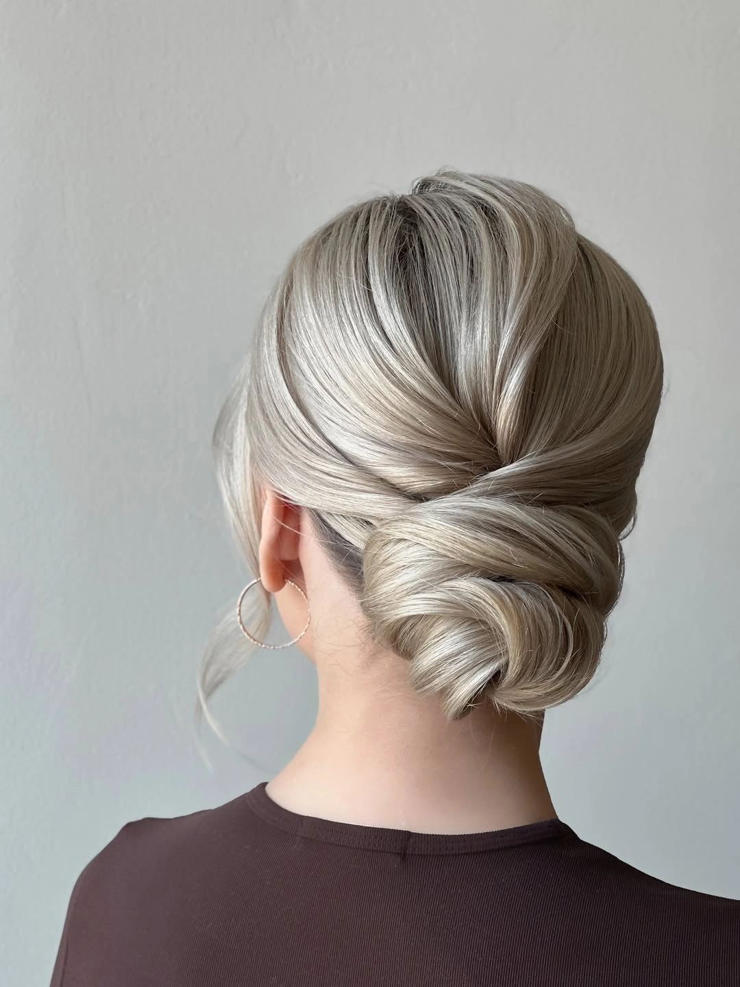 Fall hairstyles for wedding guests 2026 Classic Twisted Low Chignon with Silky Blonde Finish