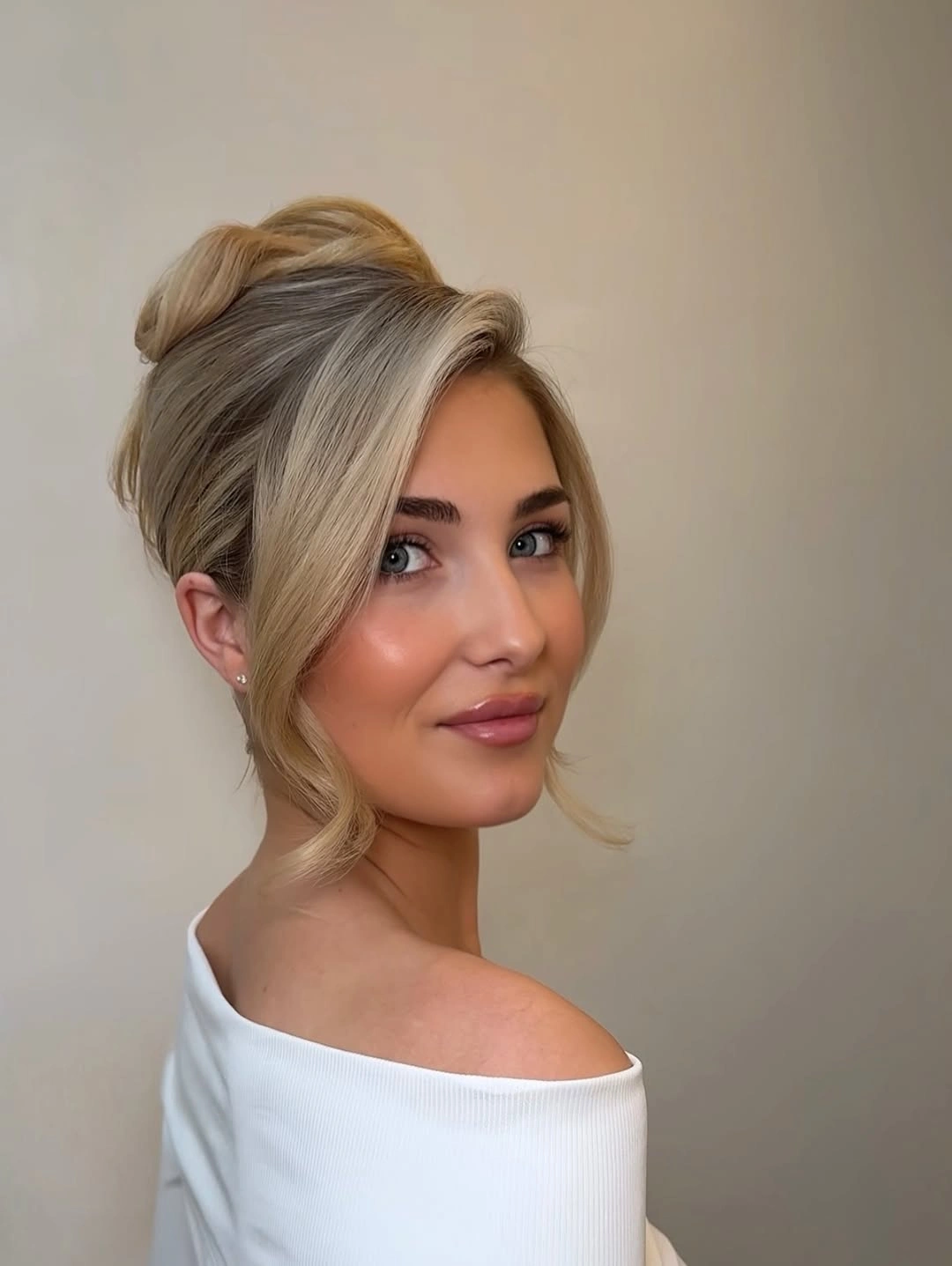 Fall hairstyles for wedding guests 2026 Elegant Twisted High Bun with Soft Curtain Pieces