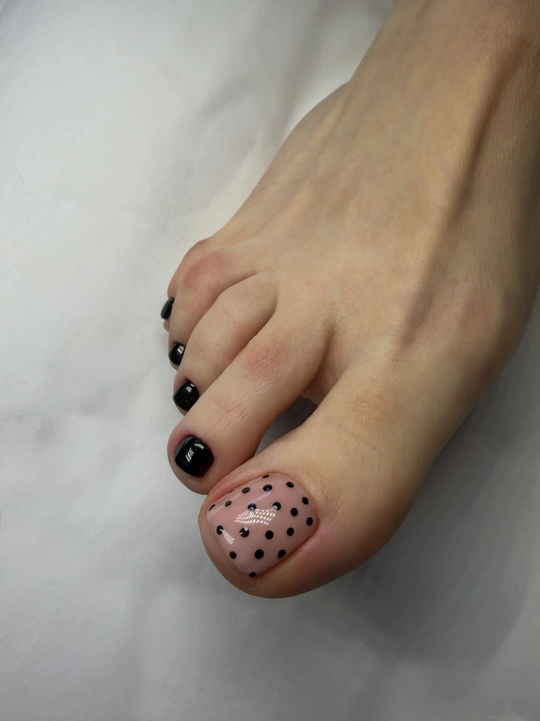 black pedicure with nude polka dot big toe