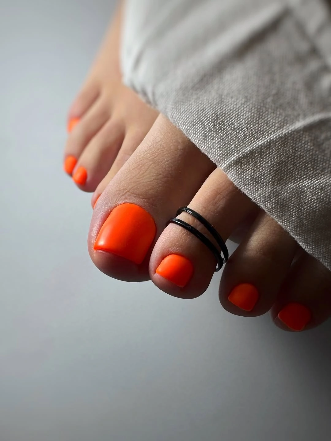 bright orange pedicure with neutral fabric styling