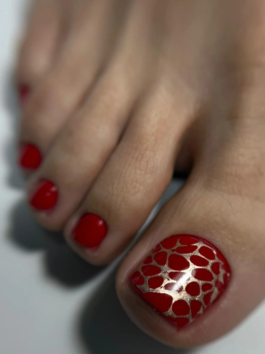 red pedicure with gold patterned big toe accent