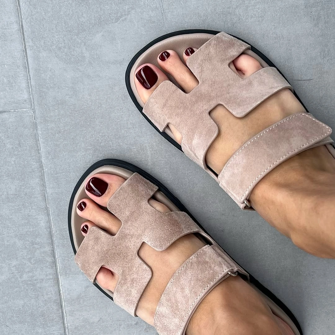 burgundy pedicure visible through taupe fall sandals