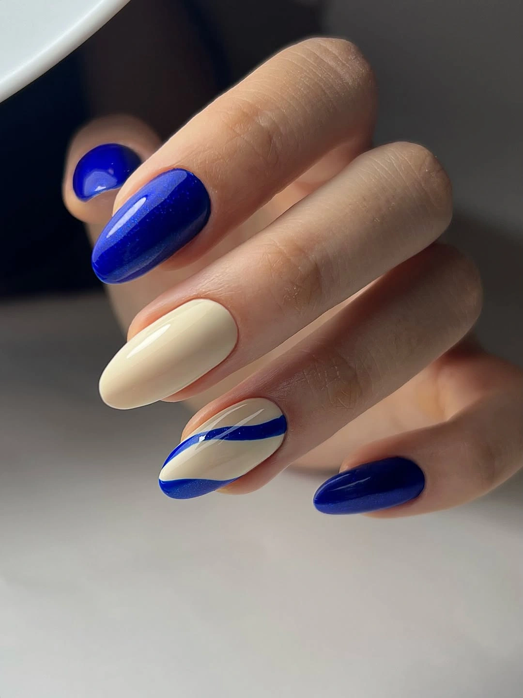 September nails color 2026 Cobalt And Cream Almond Nails With Wavy Lines