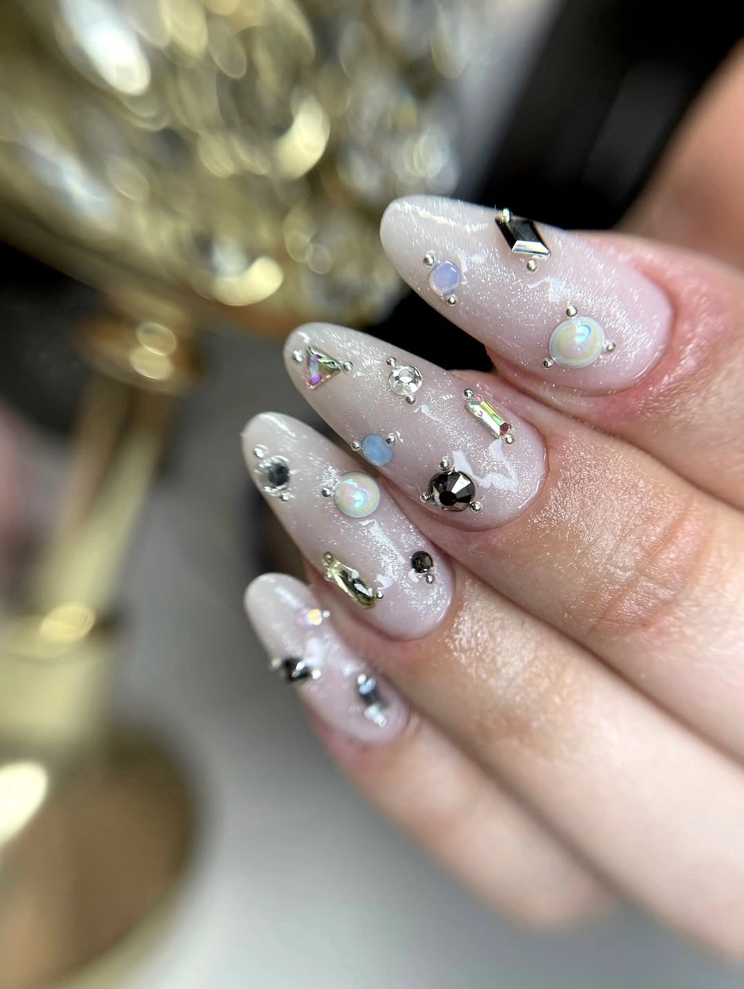 Milky pale nails with scattered silver and pastel accents