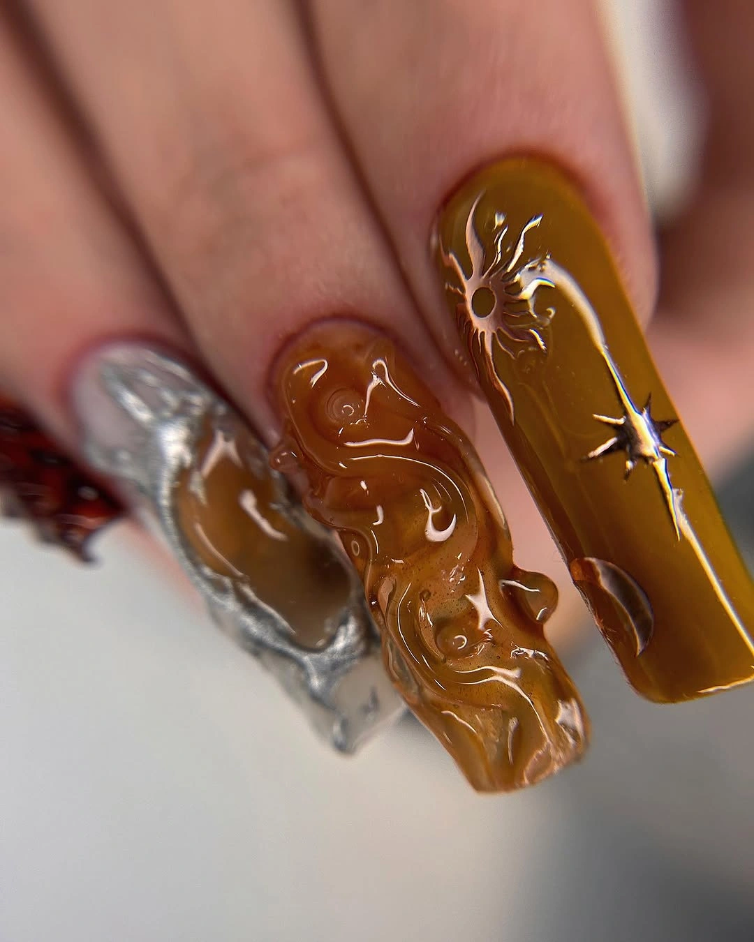 Long amber-brown nails with abstract decorative accents
