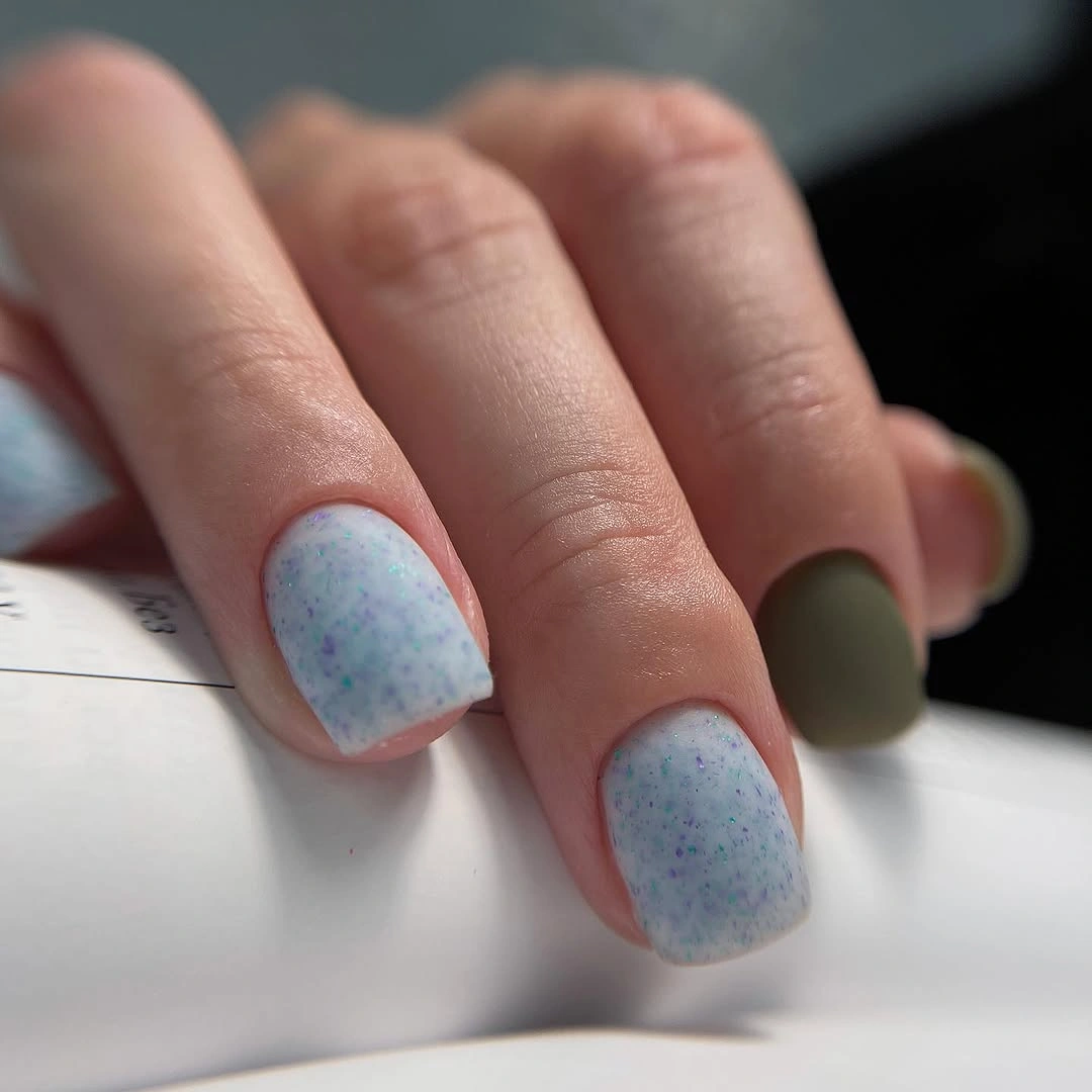 Short pale blue speckled nails with an olive accent