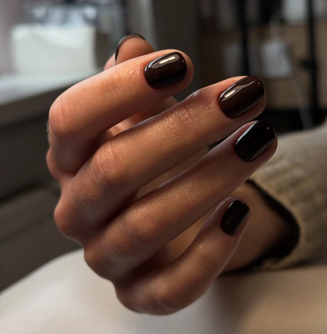 long square burgundy brown nails beside warm gold jewelry