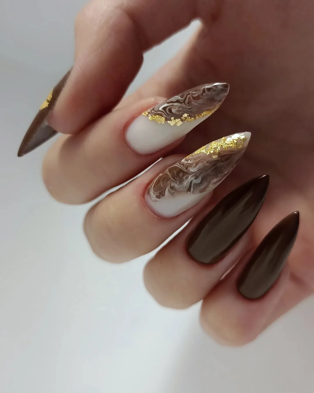 long almond chocolate nails with gold marbled accents