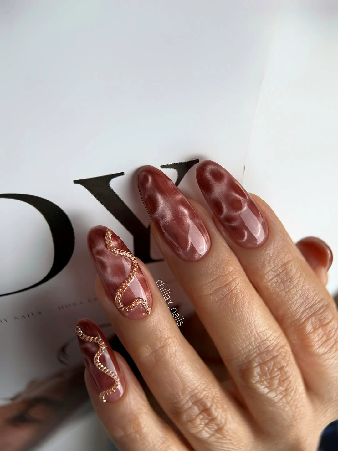 short square nails in glossy brown beside leather styling