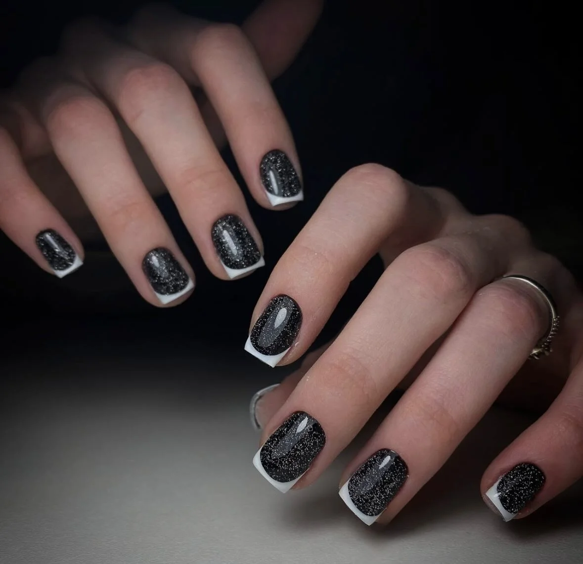 Short black nails with narrow silver glitter edge accents