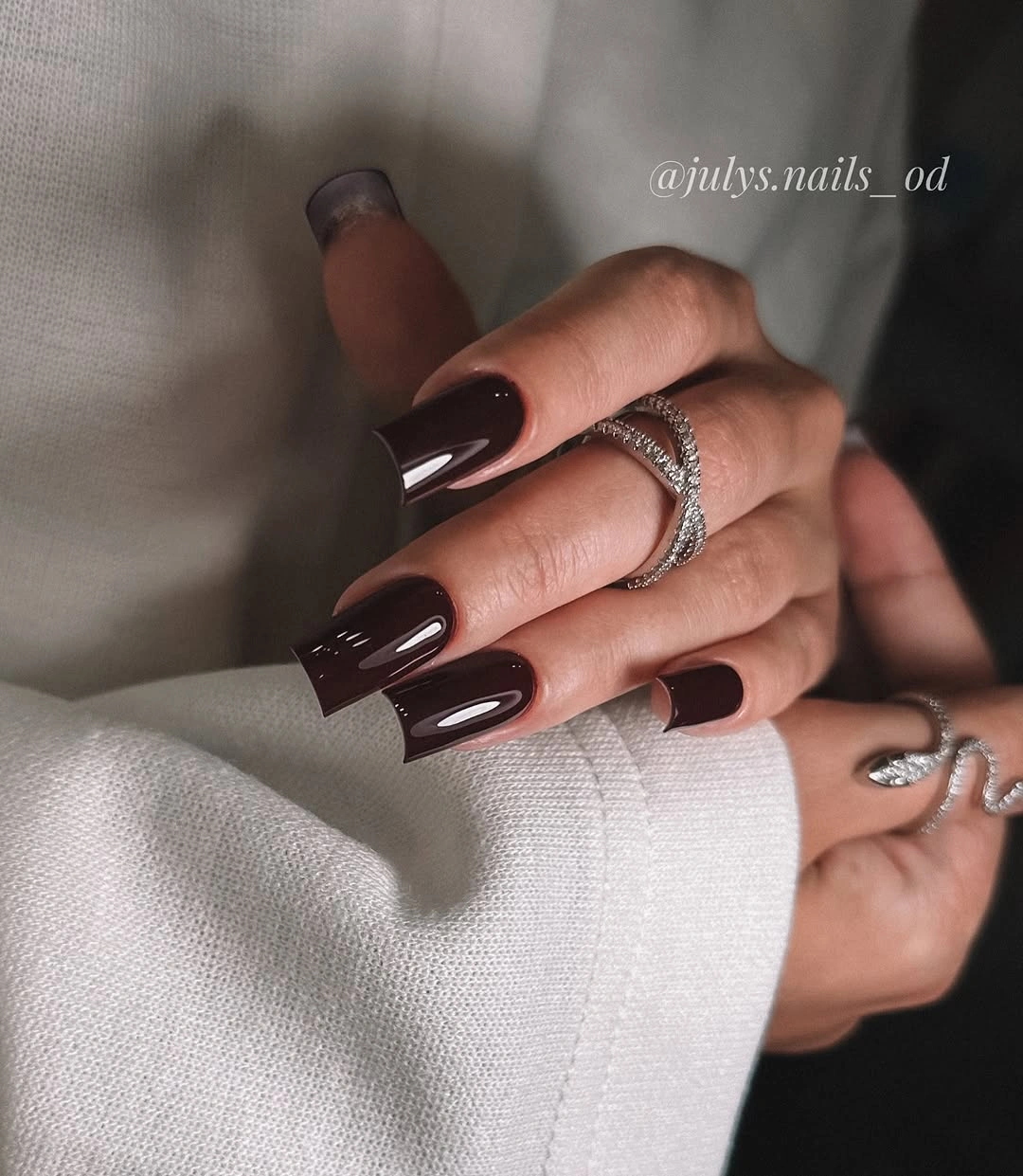 Medium-long glossy burgundy almond nails with silver rings
