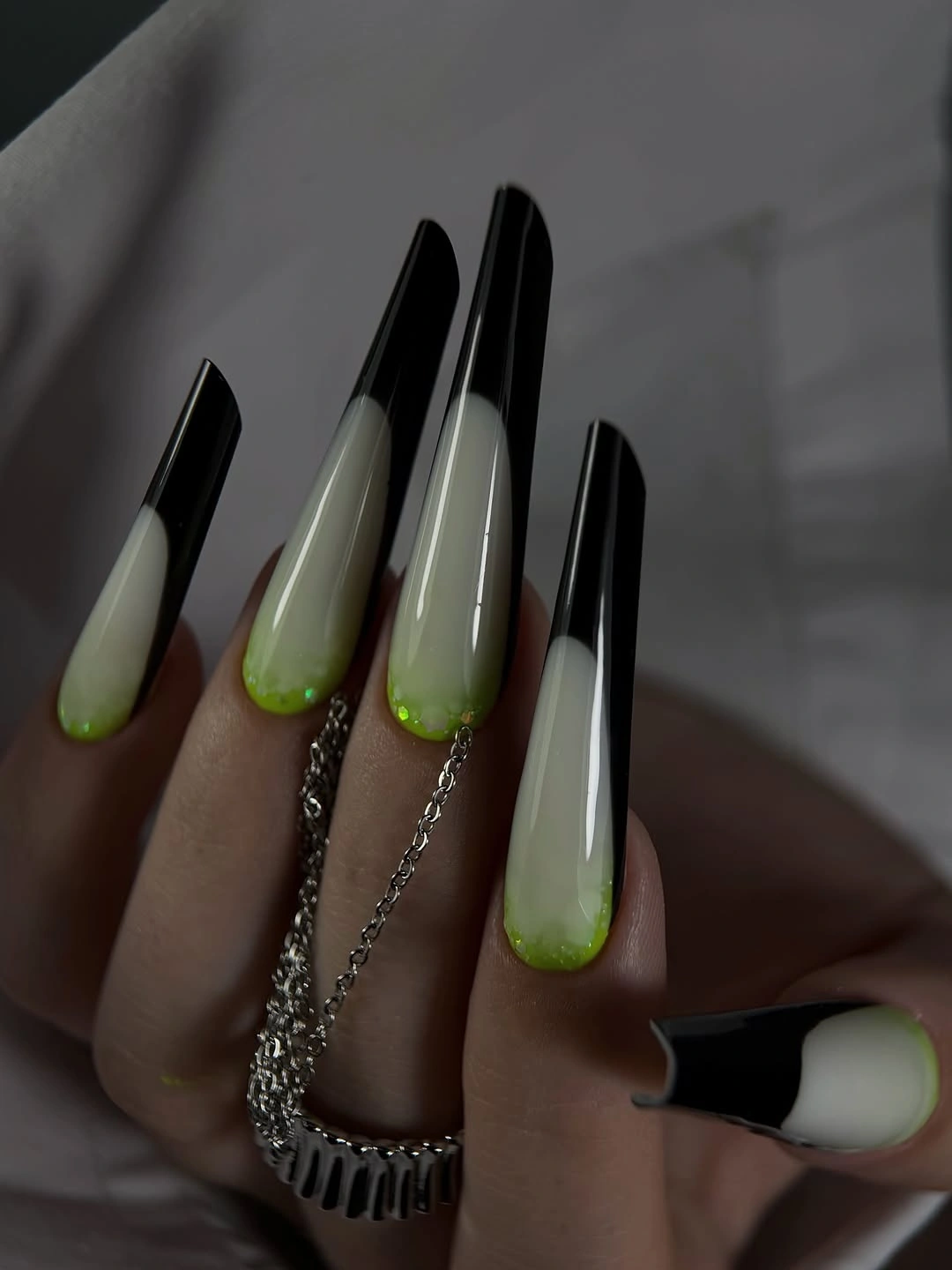 Very long black nails ending in pale green tapered tips