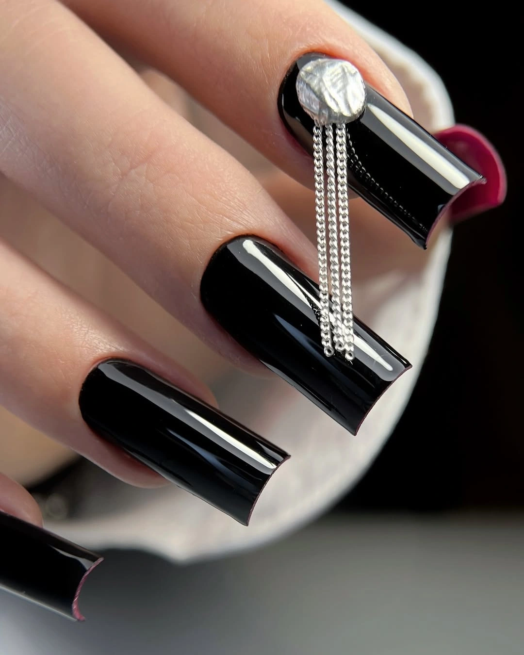 Long glossy black square nails with an oversized silver accent