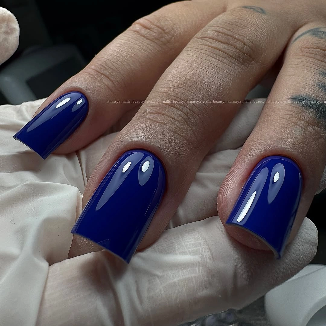 Medium glossy cobalt-blue nails with broad reflective highlights