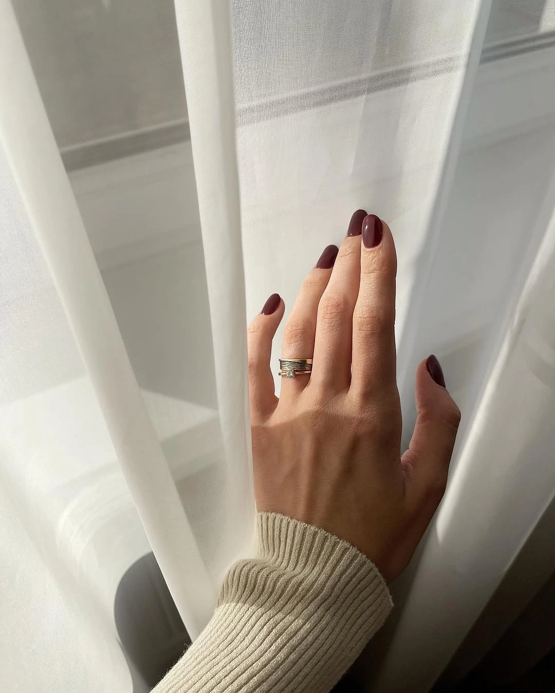 Long glossy dark brown almond nails with cream knit styling