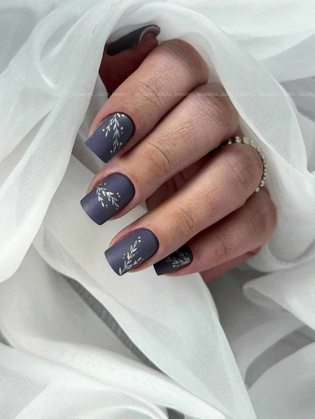 Short muted navy nails with sparse white curved accents