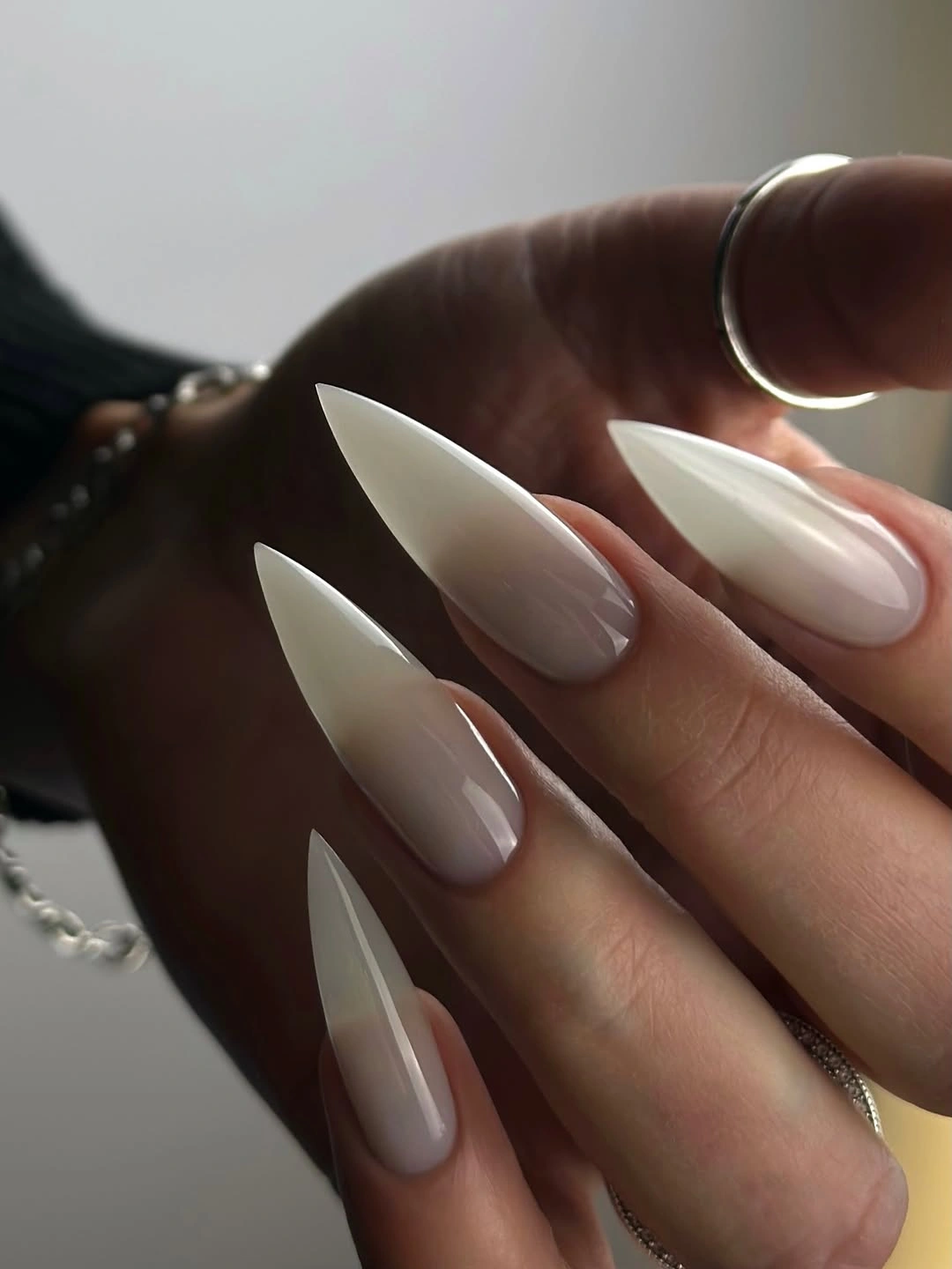 Very long milky-white pointed nails in dramatic side light