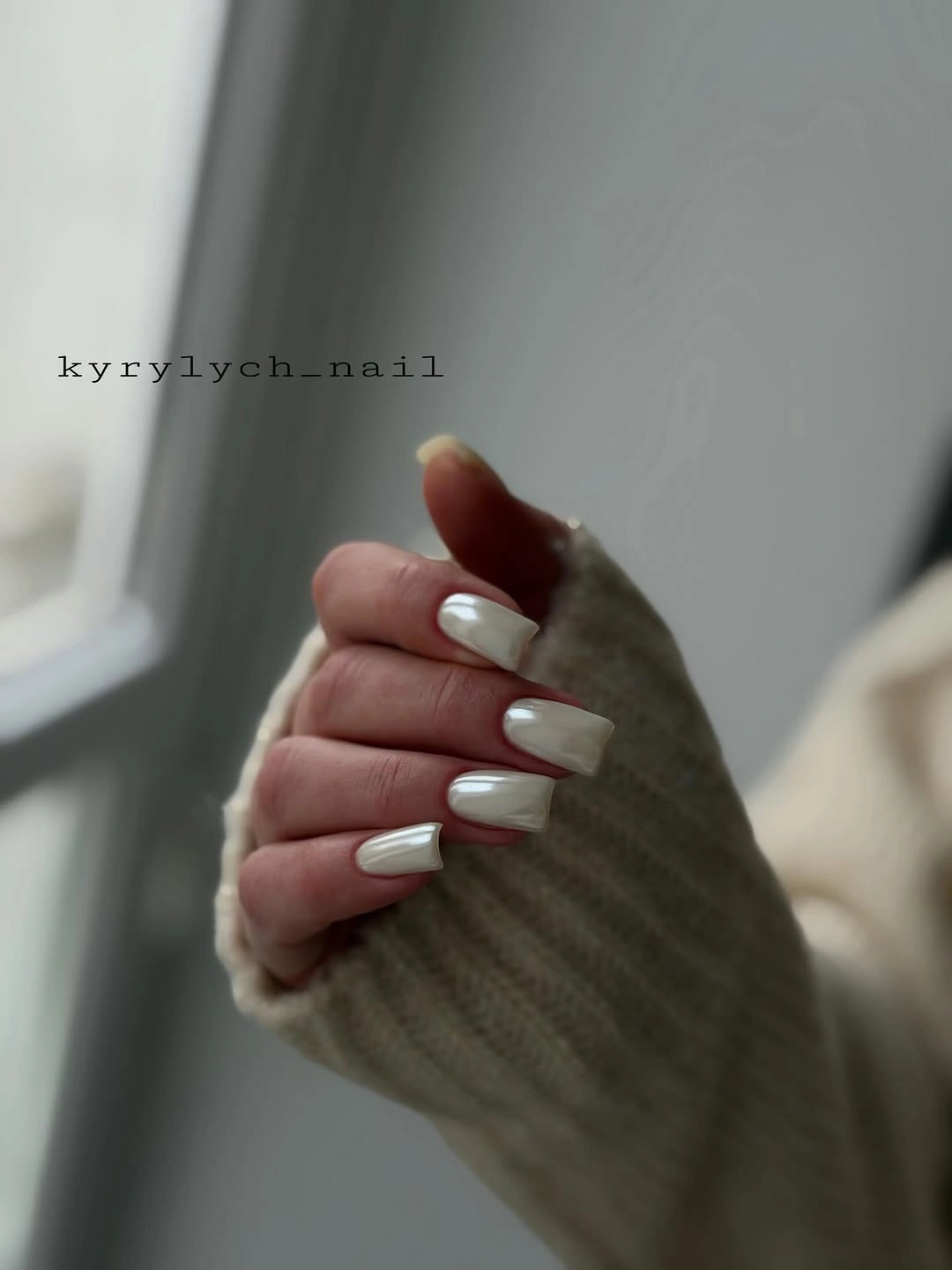 Long milky-white square nails styled with a soft knit sleeve