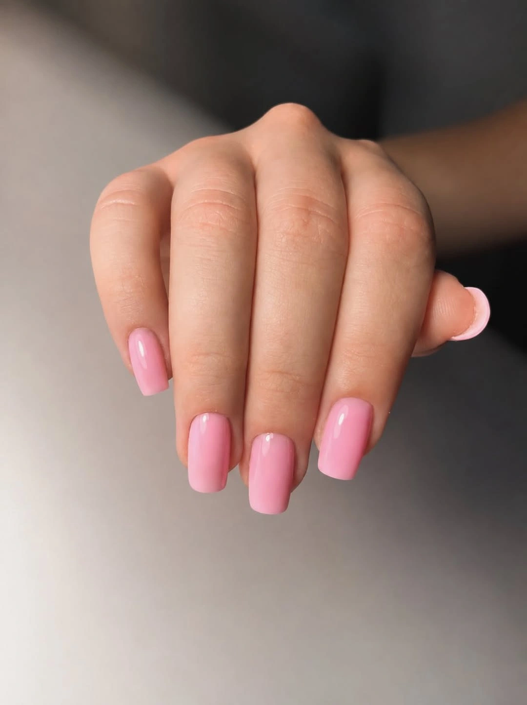 Short glossy pink rounded-square nails in a simple set