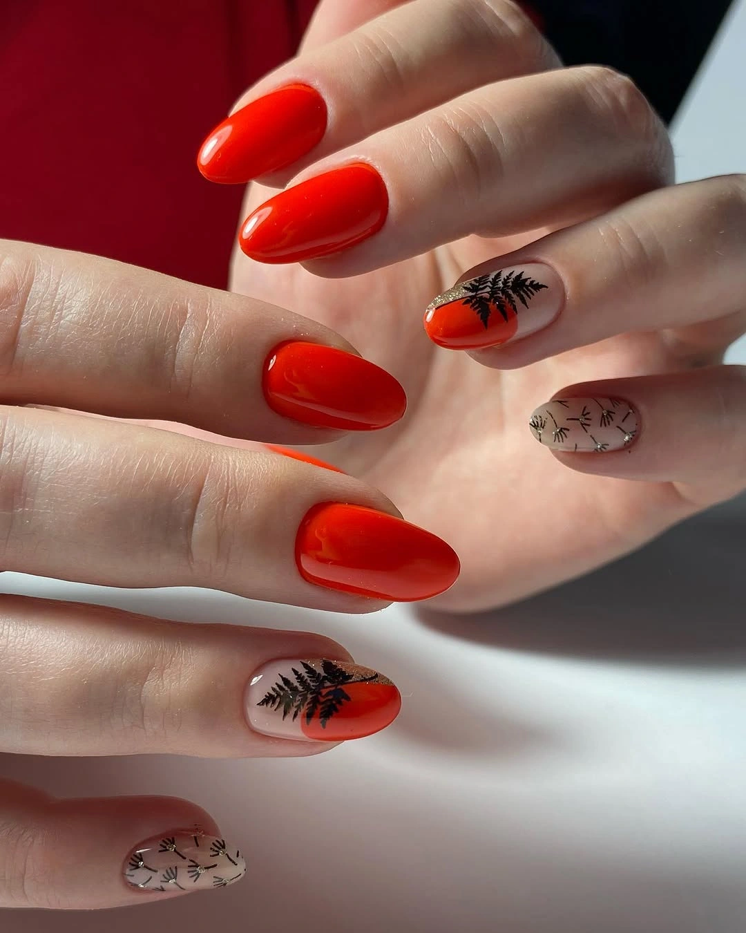 Red-orange almond nails with small black and pale illustrated accents