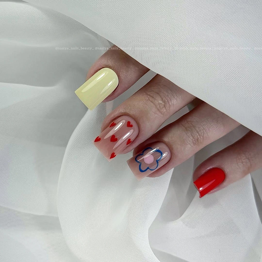 Pale yellow nails with red and white graphic accent details