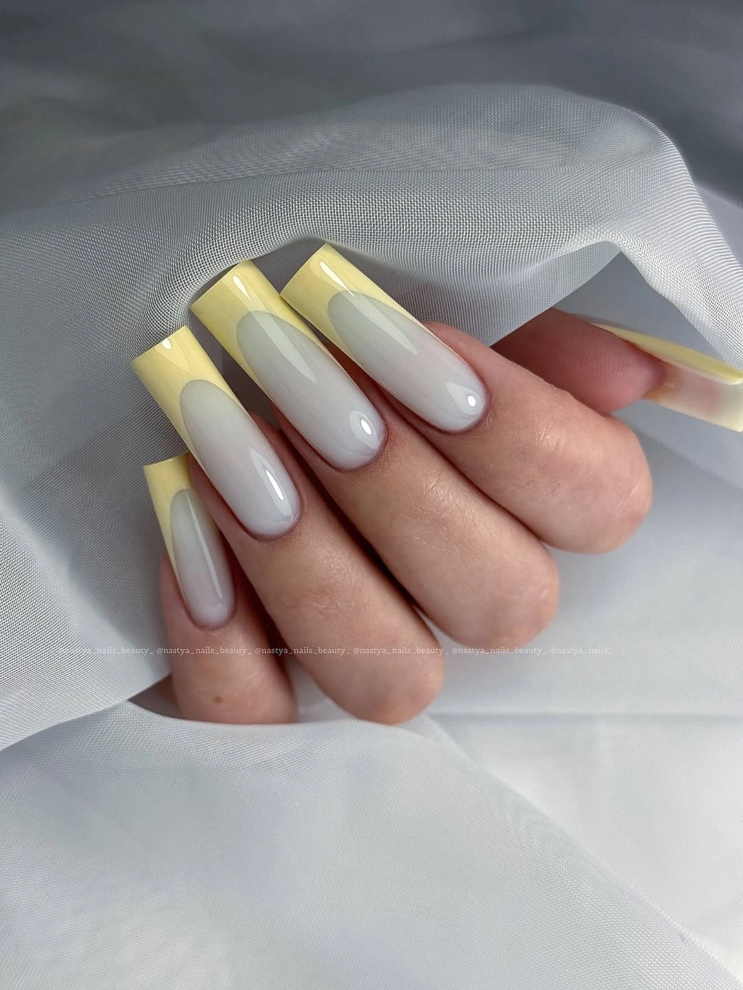 Long almond nails alternating pale yellow and milky white