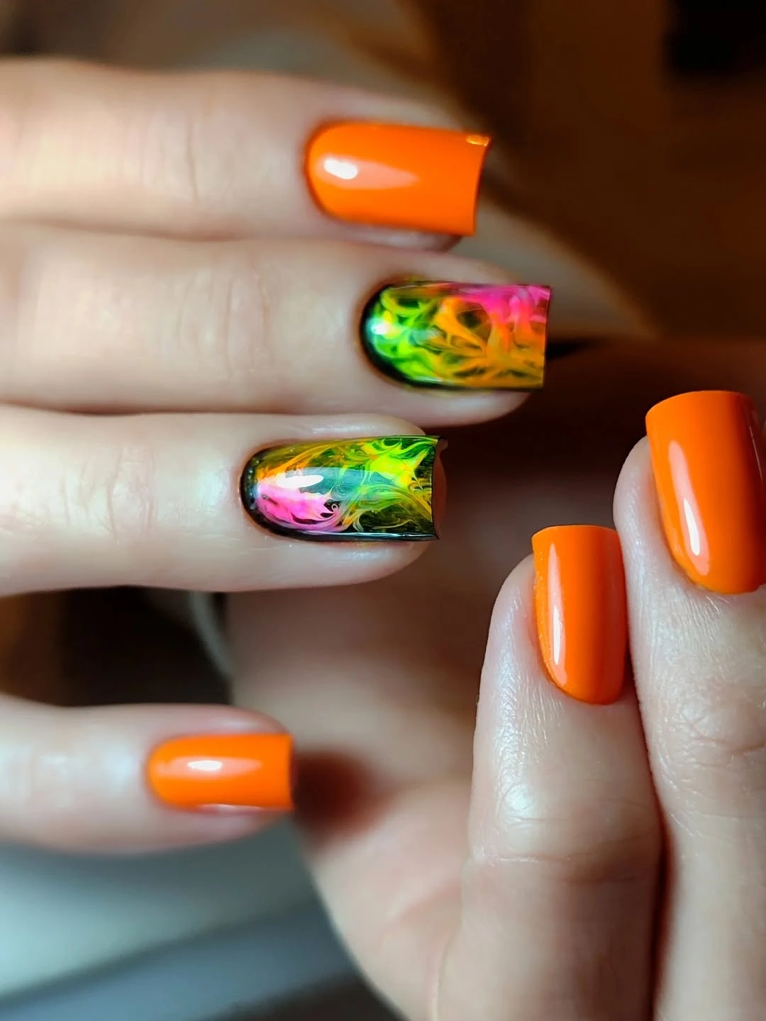 Medium square orange nails with neon marbled accent nails