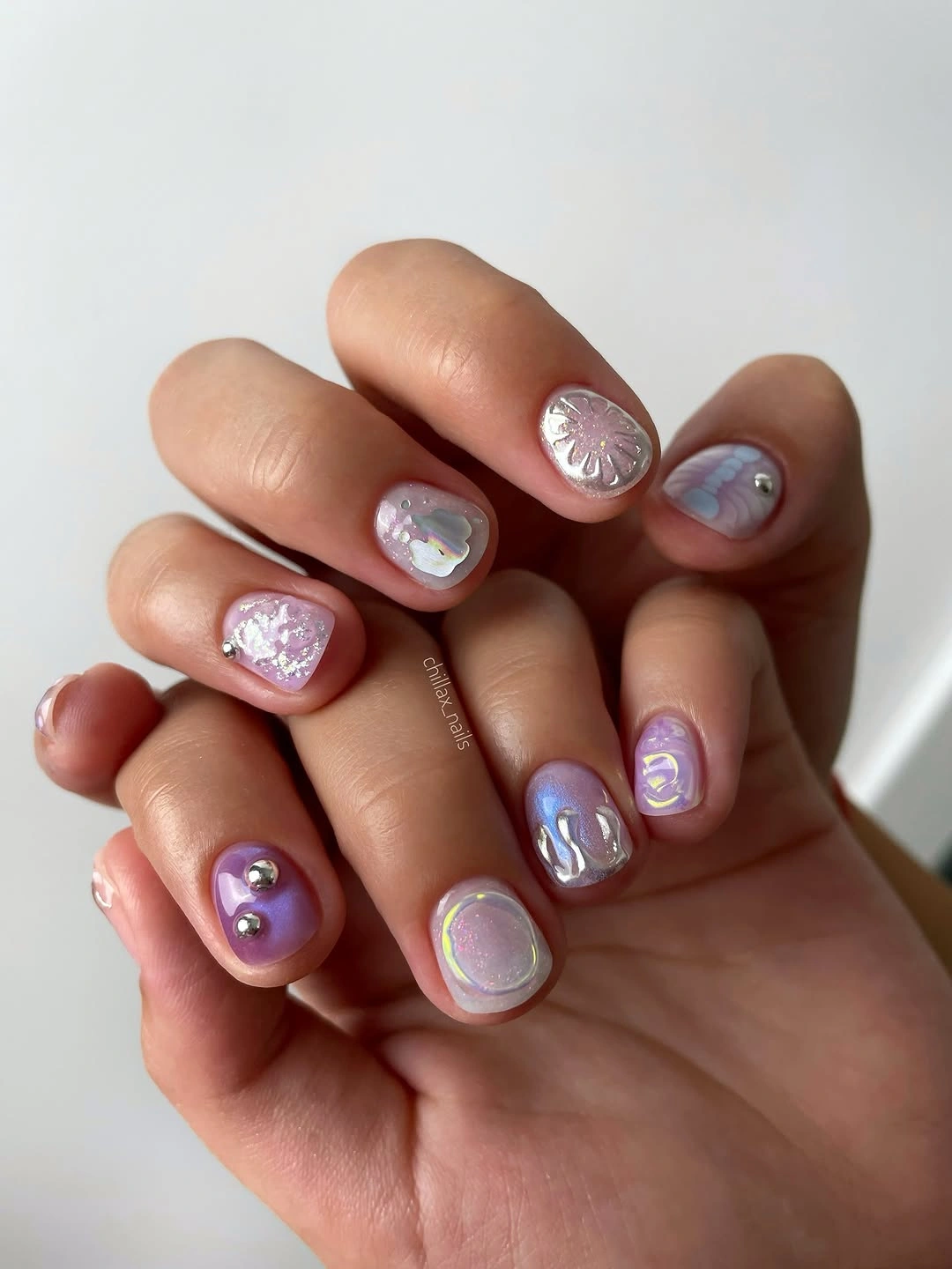 Short rounded pastel nails with small lavender pink accents