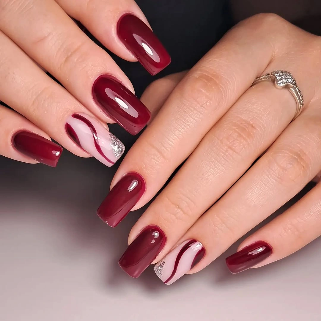 Medium square burgundy nails with pale curved accent sections