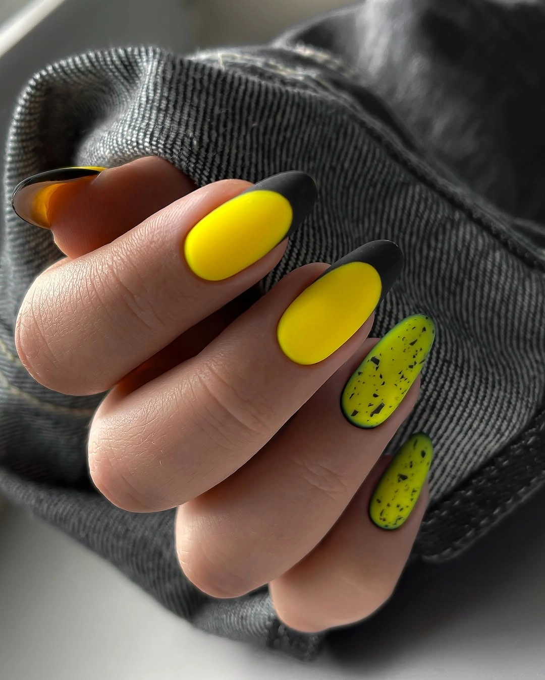 Neon yellow nails with black tips and speckled accents