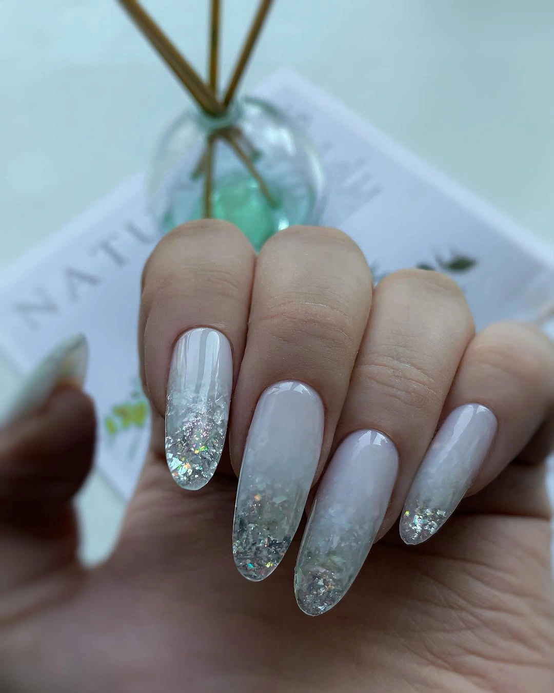 Milky almond nails with frosted silver glitter tips
