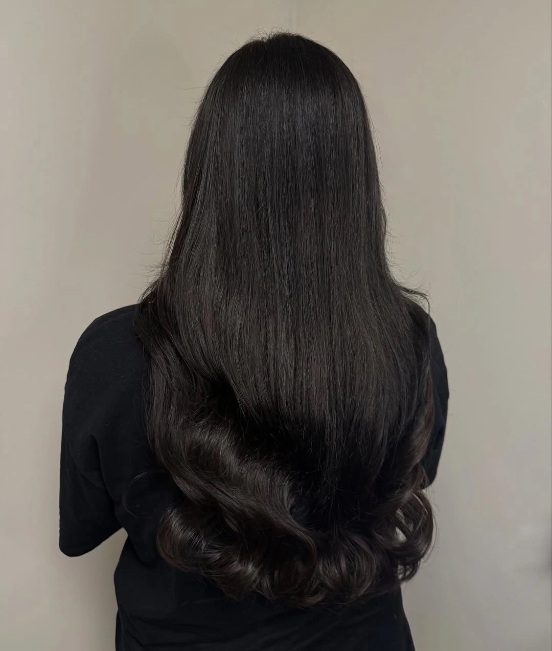 Very dark brown hair with loose curls and feathered ends
