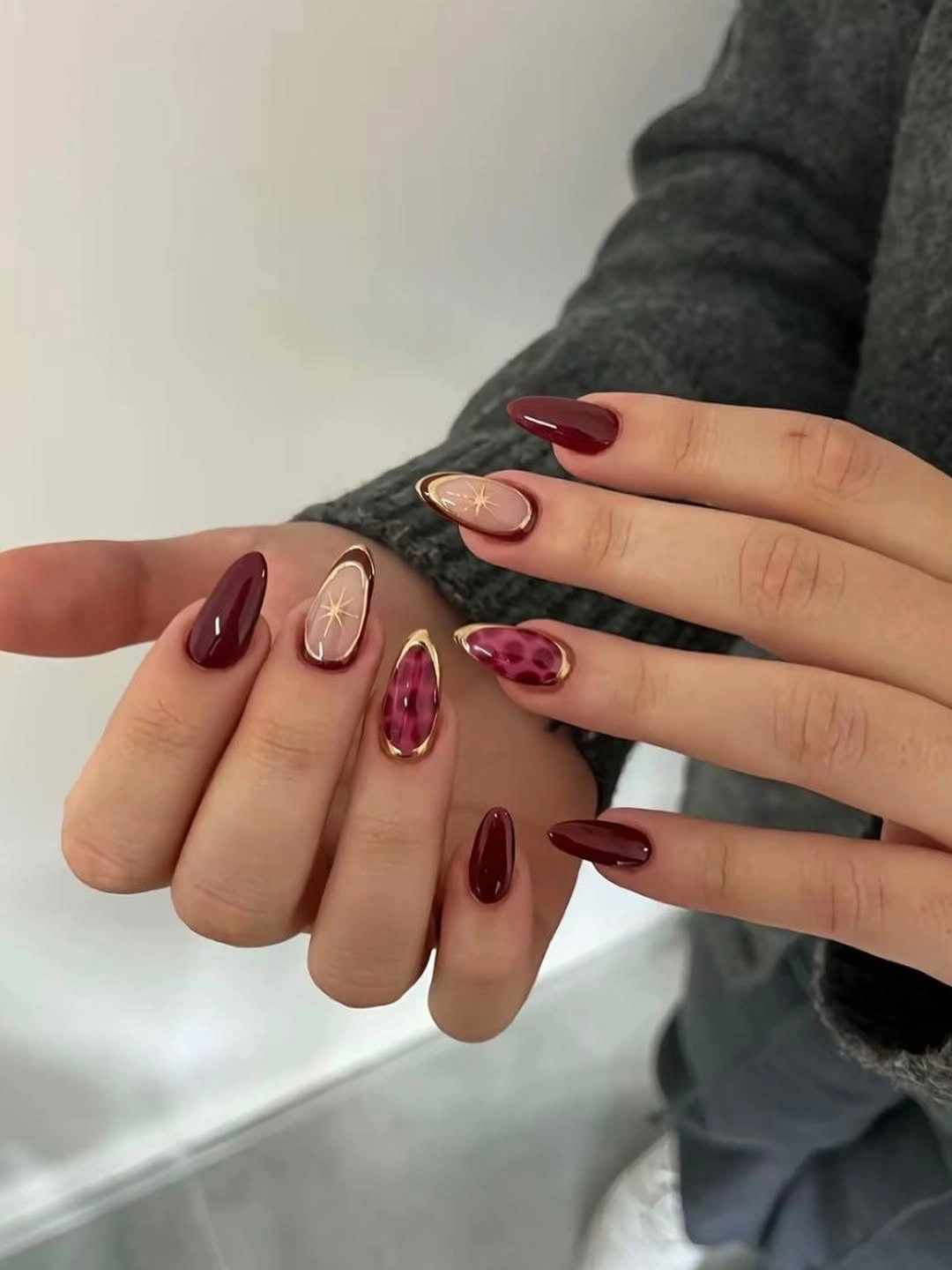 Medium almond burgundy nails with pale pink and warm accent details