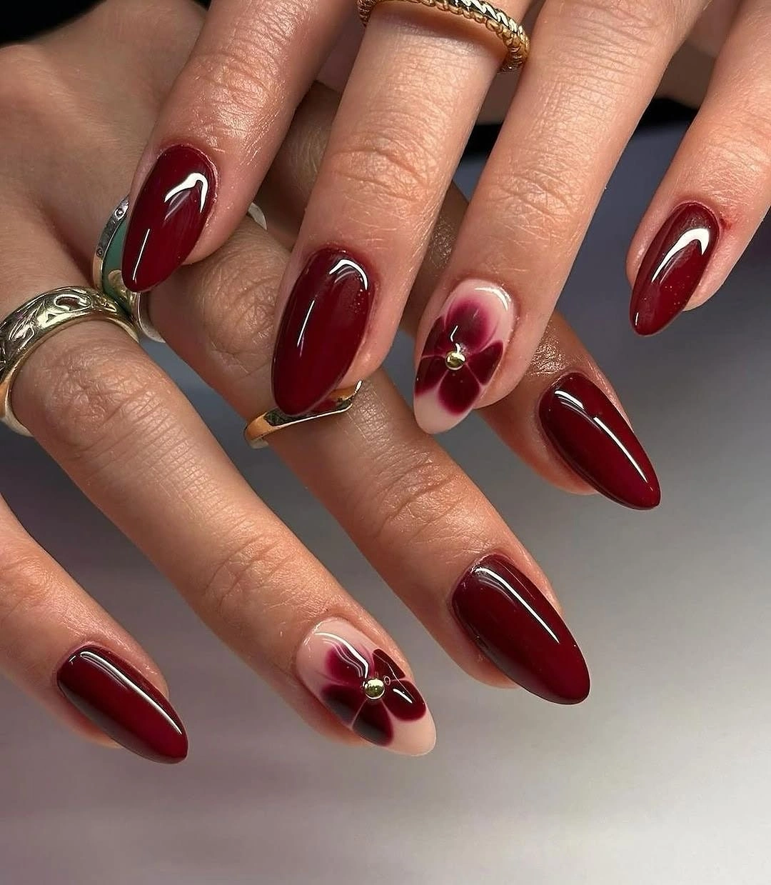 Long almond burgundy nails with pale sections and warm base accents