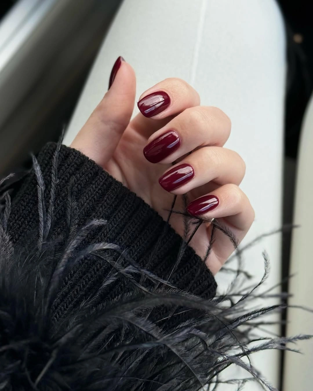 Medium almond nails with curved burgundy edges and pale linework