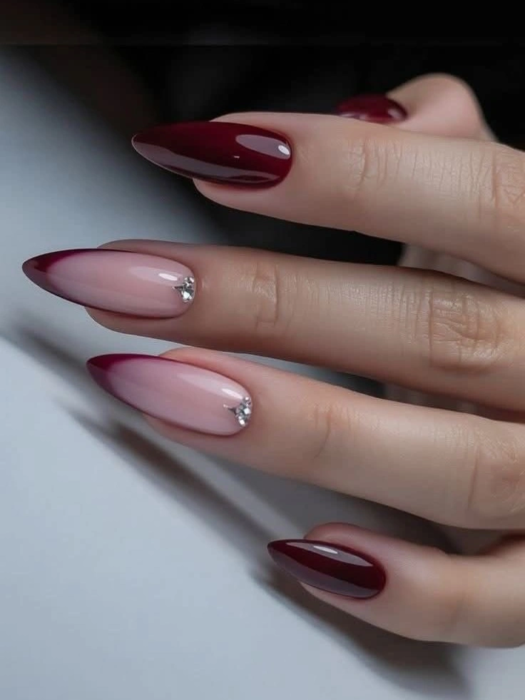 Long almond burgundy nails with pale accents and a tiny bright detail