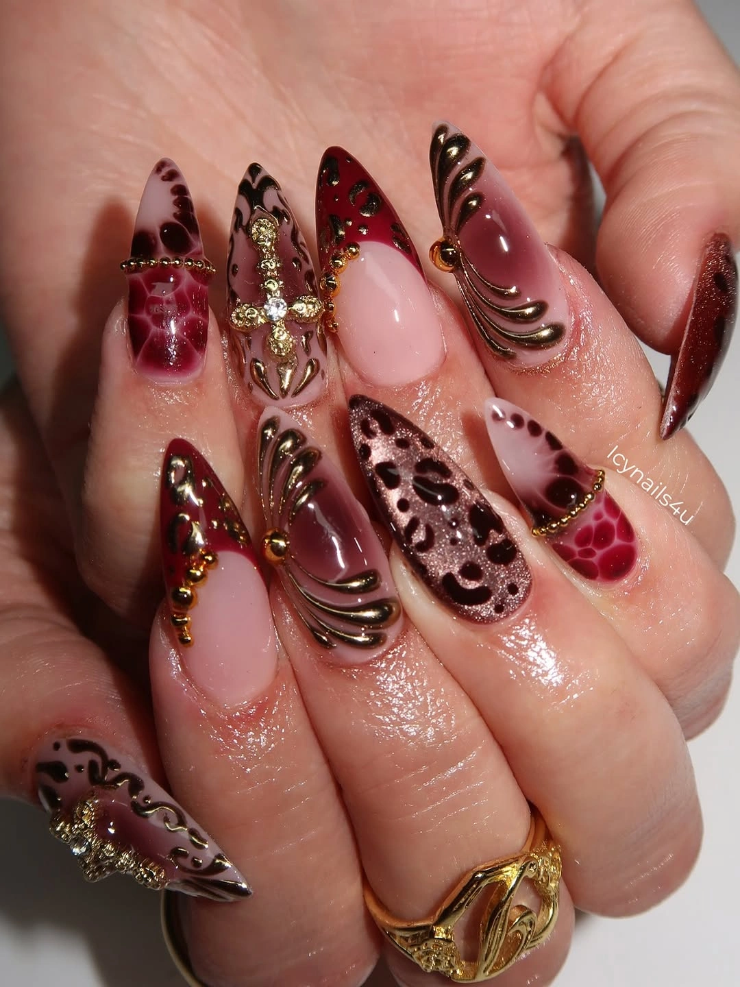Long pointed burgundy nails with spots swirls and warm embellishments