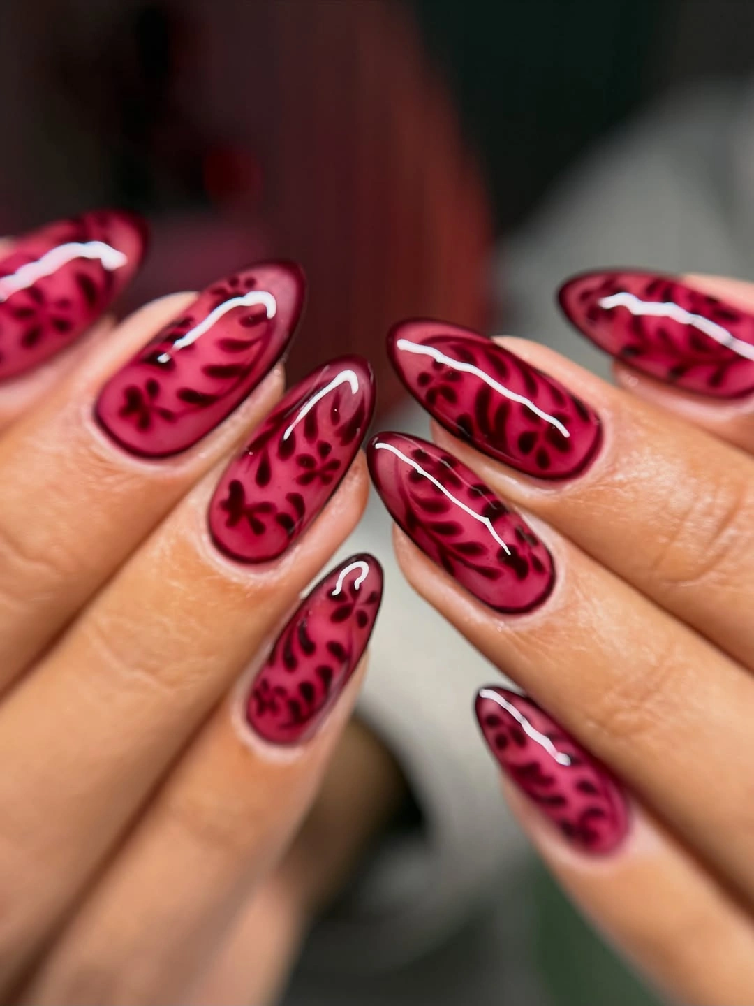 Medium almond nails with burgundy patterned tips over pale pink