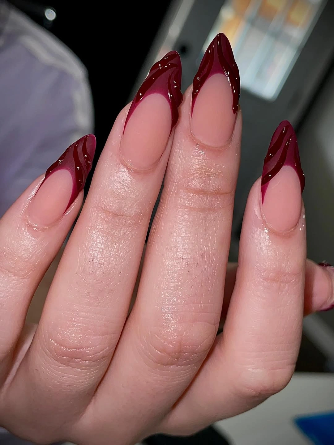 Long stiletto nails with deep burgundy French tips and sheer pink base