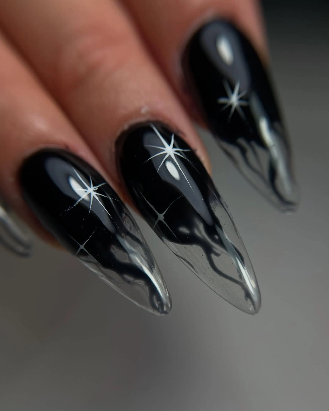 Black pointed nails with white starbursts and pale reflective tips