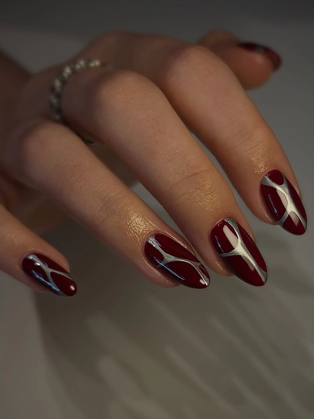 Deep wine almond nails with pale looping line accents