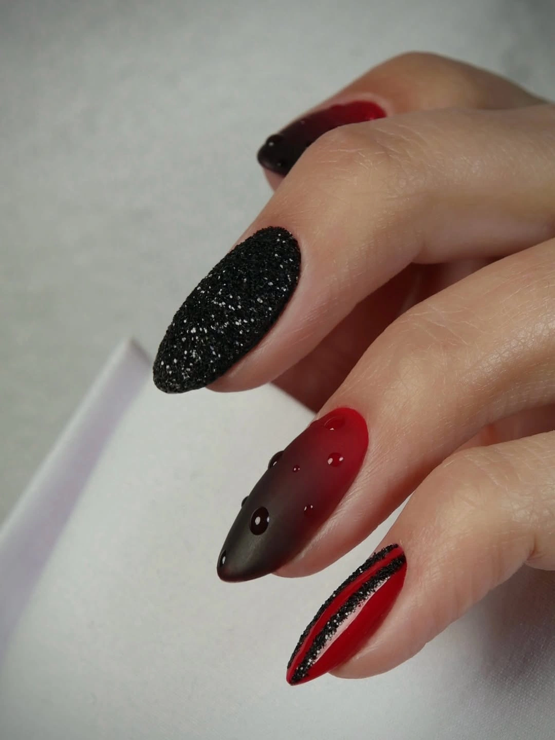 Mixed black burgundy and red nails with varied textures and accents
