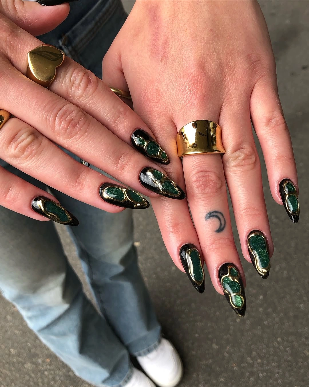 Deep green almond nails with curved gold and silver accents