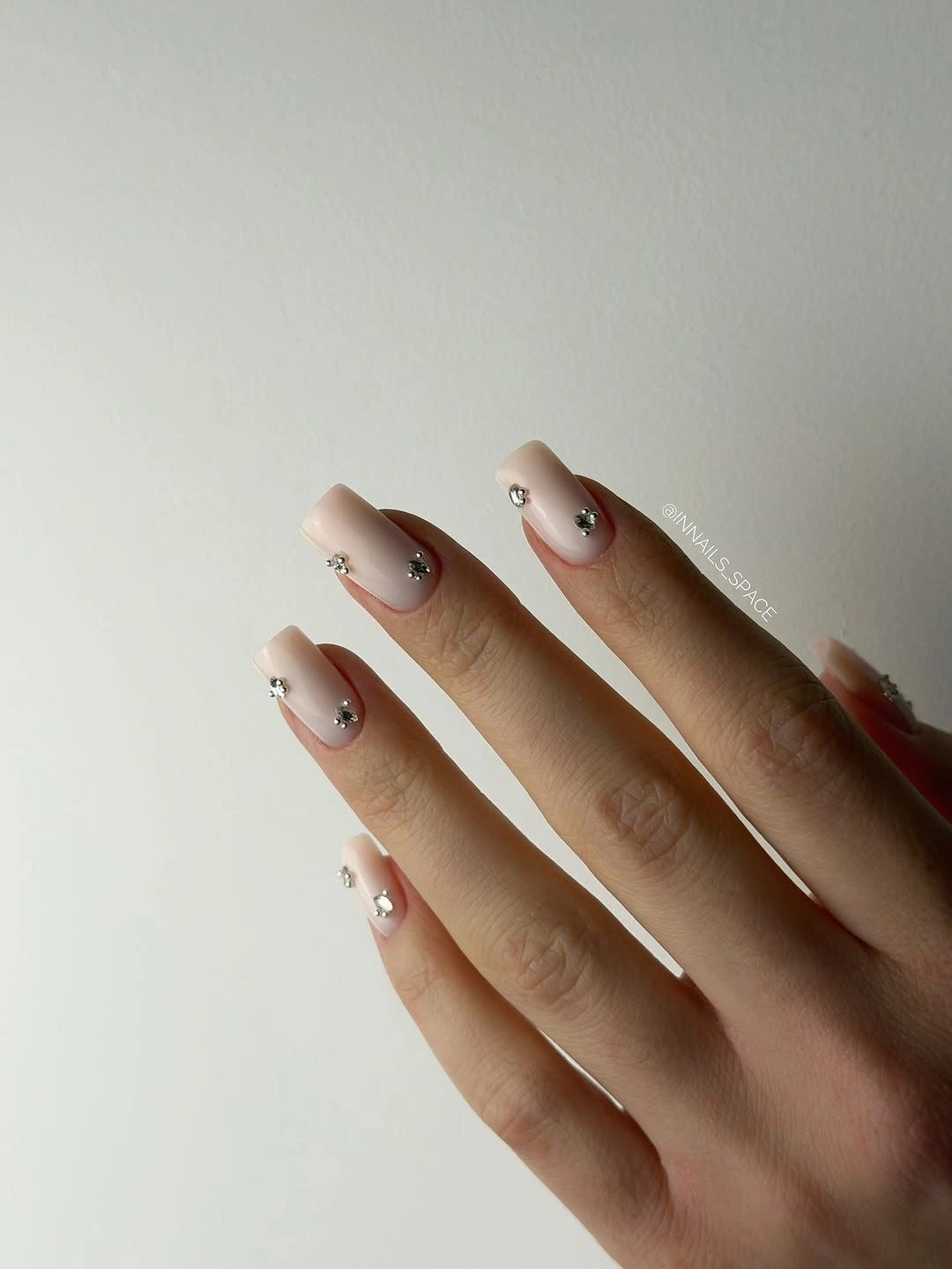 Long almond pale nails with tiny dark and metallic accents